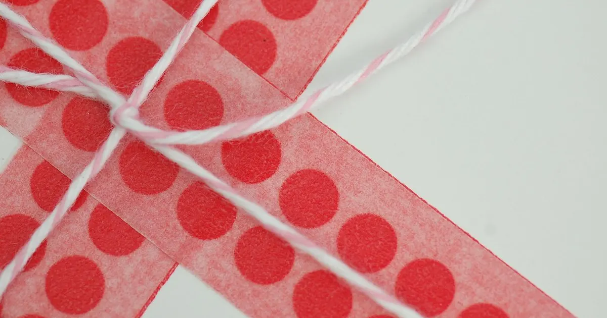 A gift wrapped in white paper with red polka-dot ribbon and twine