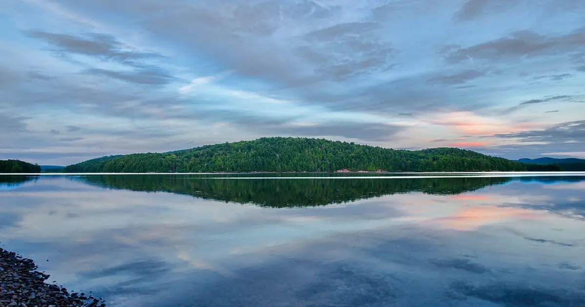 A calm lake reflecting hills and sky